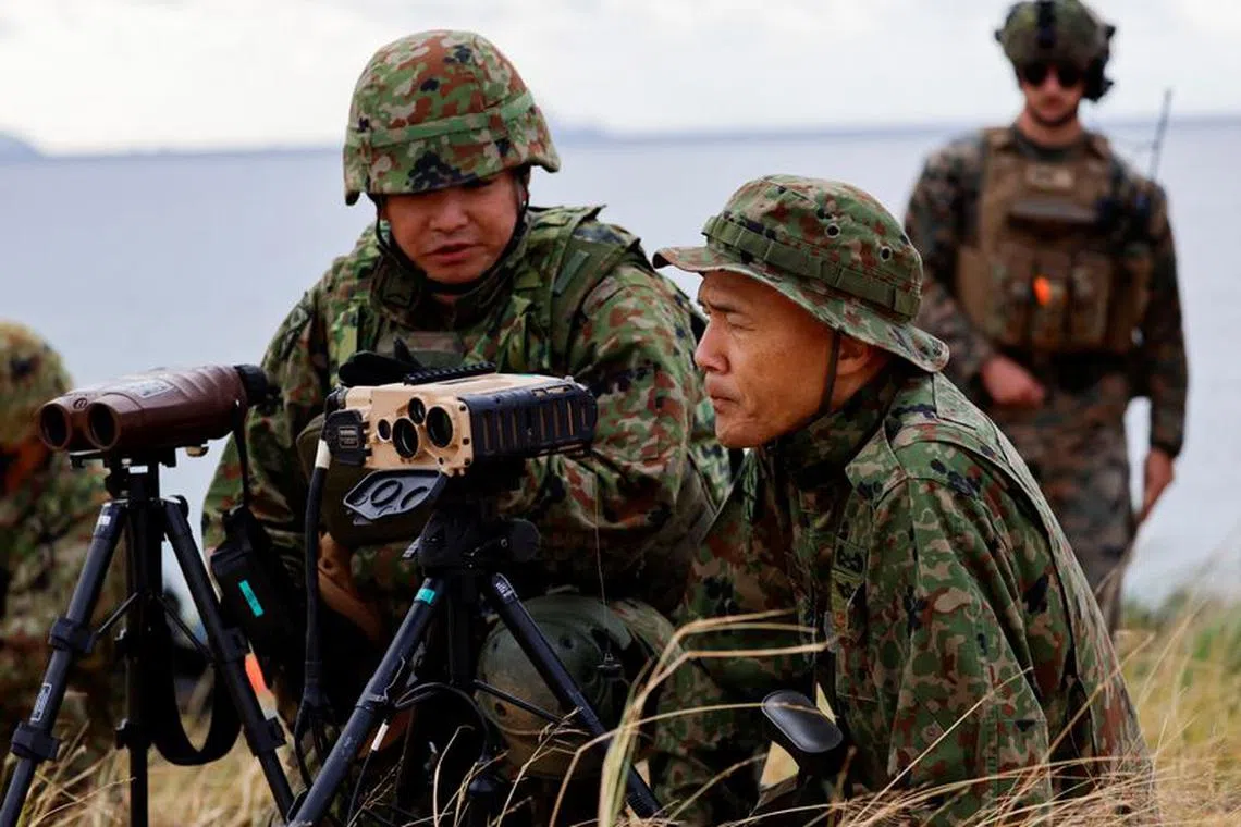 Soldiers of Japanese Ground Self-Defense Force's (JGSDF) Amphibious Rapid Deployment Brigade (ARDB), Japan's first marine unit since World War Two, take part in a military drill as a U.S. Marine personnel looks on, at an uninhabited Irisuna island close to Okinawa, Japan, November 15, 2023. REUTERS/Issei Kato