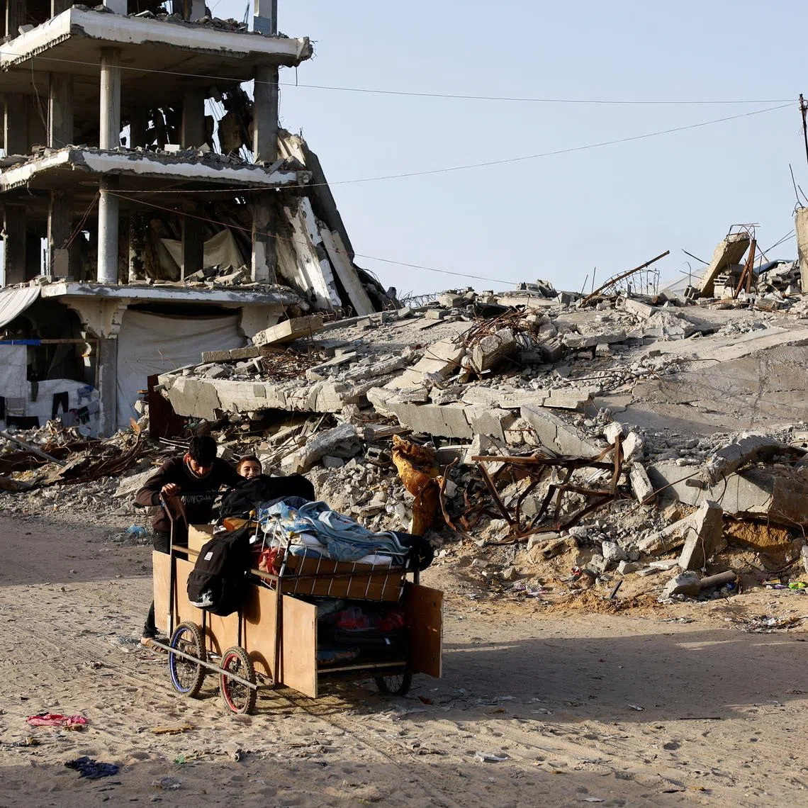 Palestinians push a cart past the rubble of residential buildings destroyed during the two-year Israeli offensives, in Gaza City, February 17, 2026. REUTERS/Mahmoud Issa