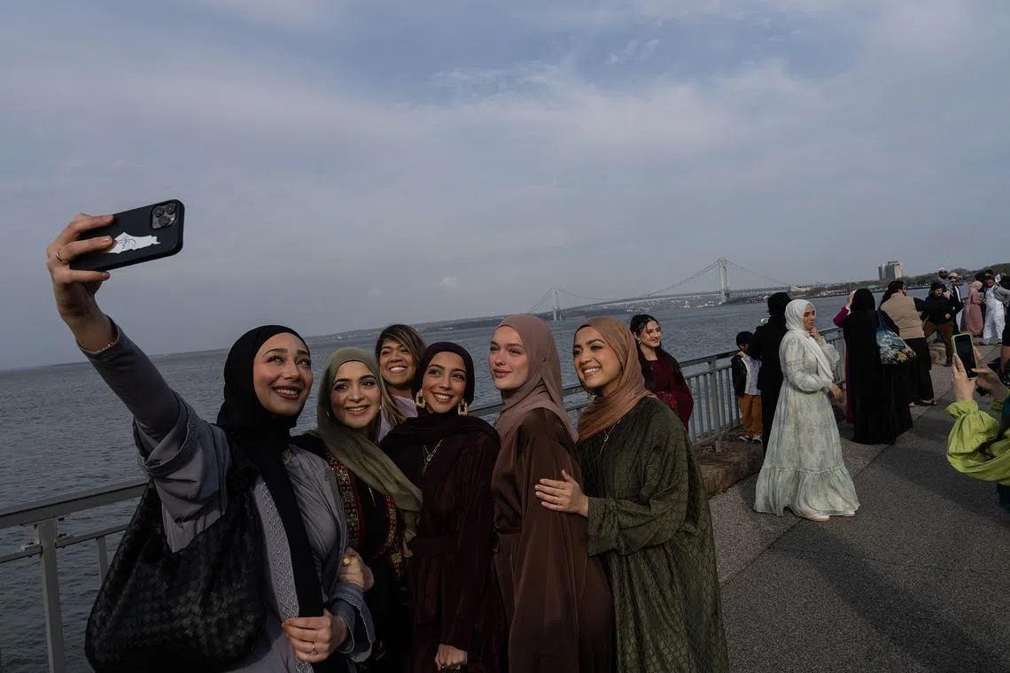 Women taking selfies after taking part in Eid al-Fitr prayers in the Brooklyn borough of New York, on April 10, 2024. 