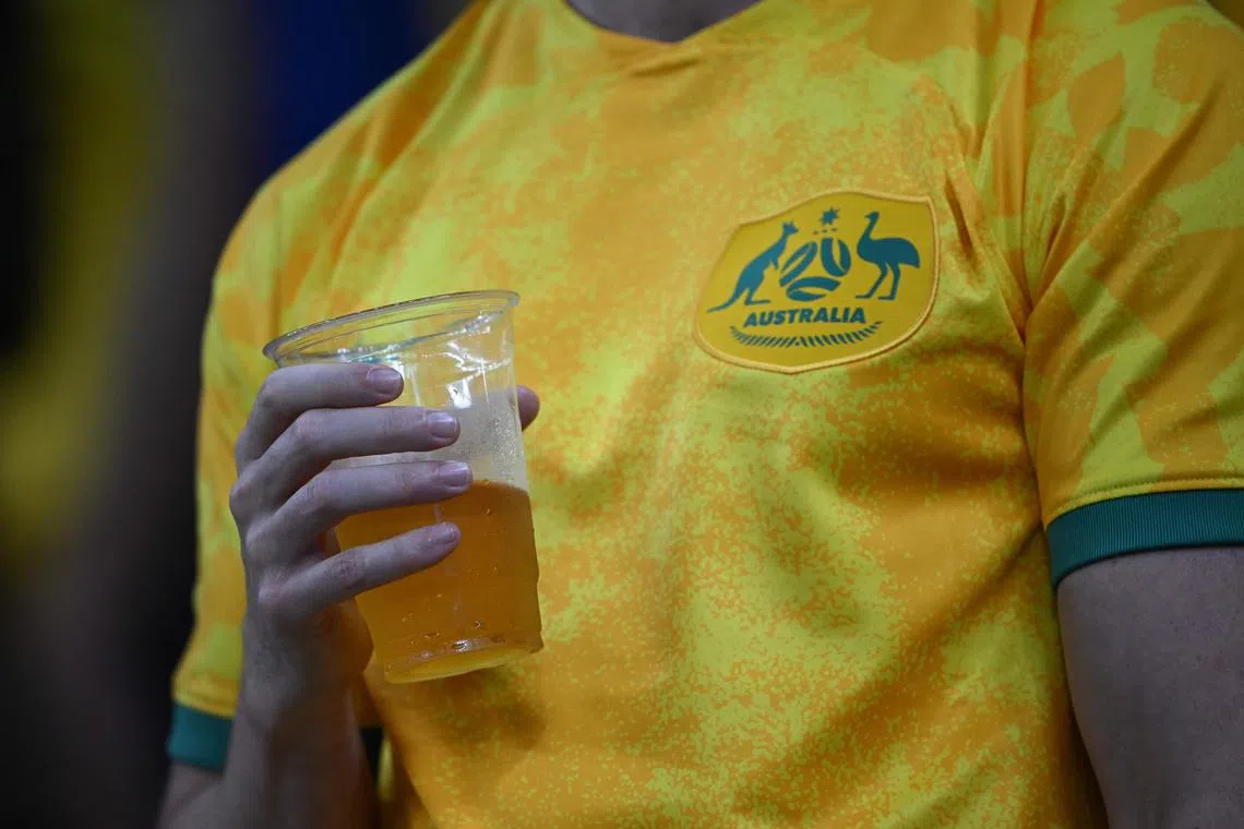 An Australia suporter holds a non-alcoholic beer as he waits for the start of the World Cup Group D match between Australia and Denmark at the Al-Janoub Stadium in Al-Wakrah.