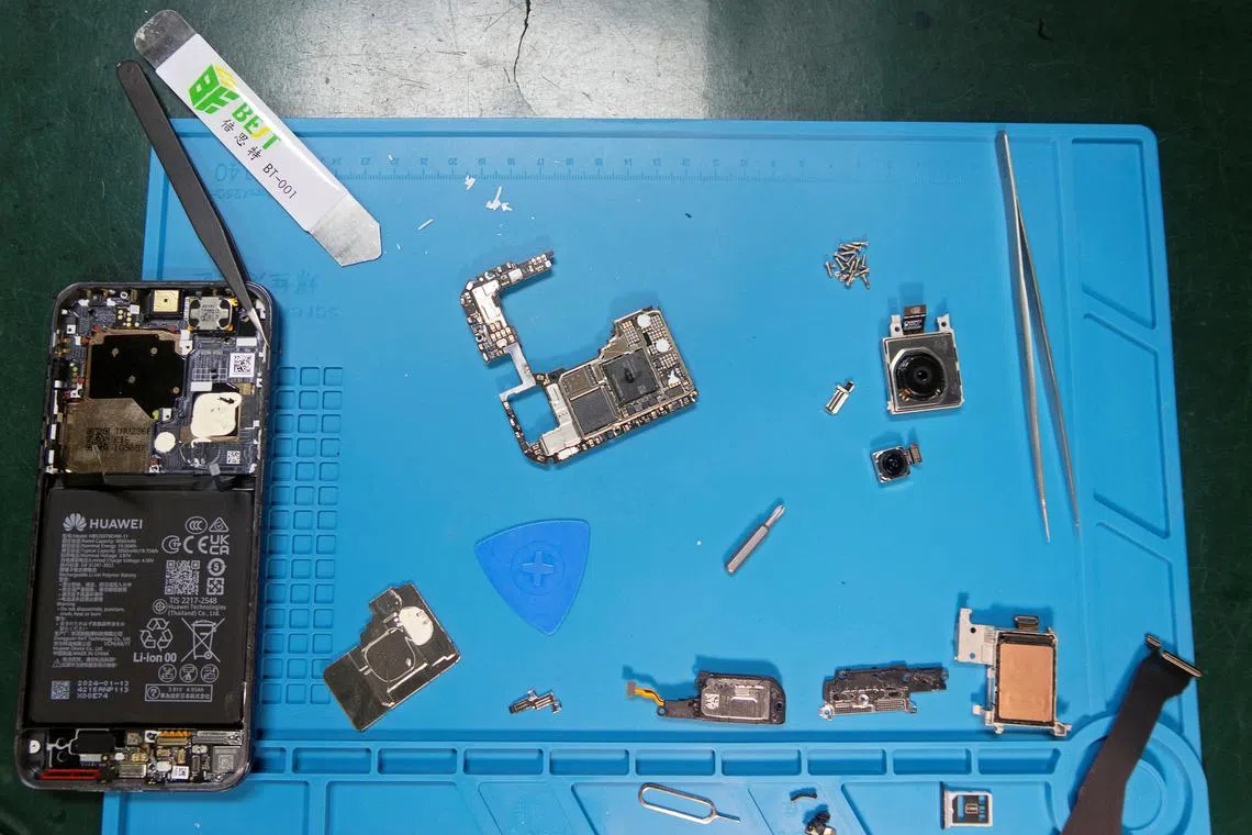 Components of a Huawei Pura 70 Pro smartphone are laid out on a table during a teardown analysis by iFixit.