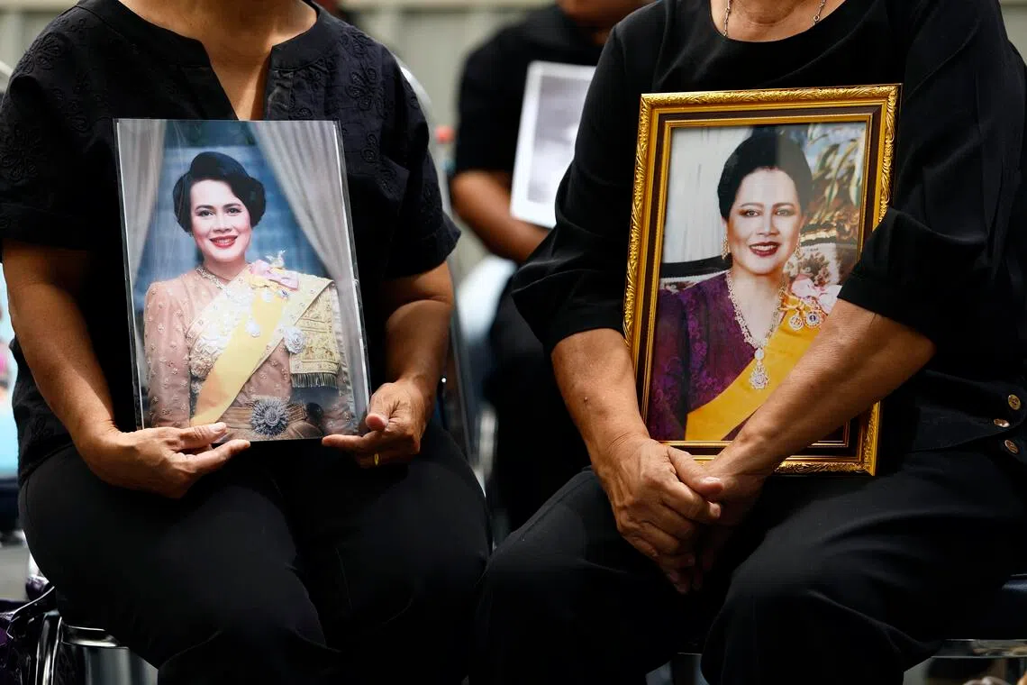 Thai women mourn with photographs of Thailand's Queen Mother Sirikit after the announcement of her death at King Chulalongkorn Memorial Hospital in Bangkok on Oct 25.