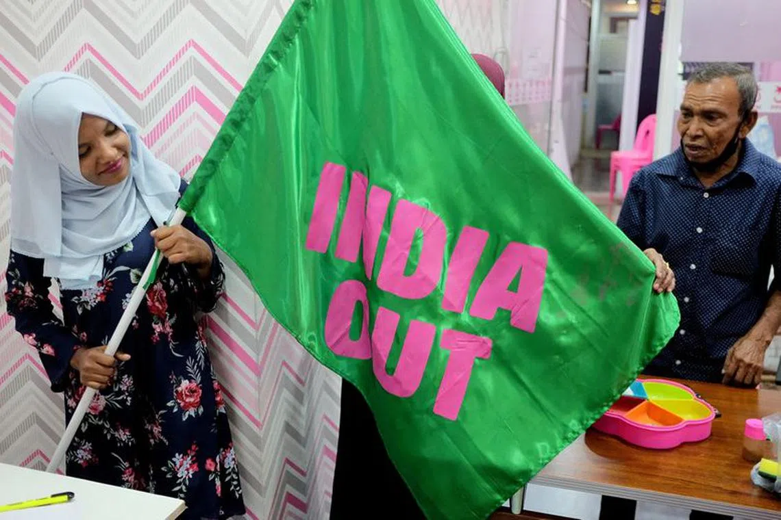 FILE PHOTO: A Progressive Party of Maldives worker poses with an \"India Out\" flag in Male, Maldives, March 21, 2022. Picture taken March 21, 2022. REUTERS/Alasdair Pal/File Photo