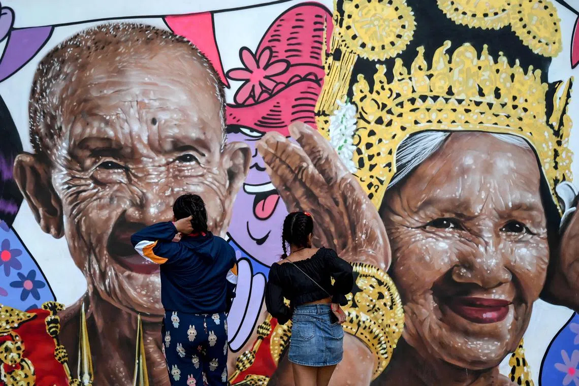 Pedestrians looking at a billboard displaying images of elderly people for the New Year celebrations in Phnom Penh, Cambodia on Jan 2, 2025. 