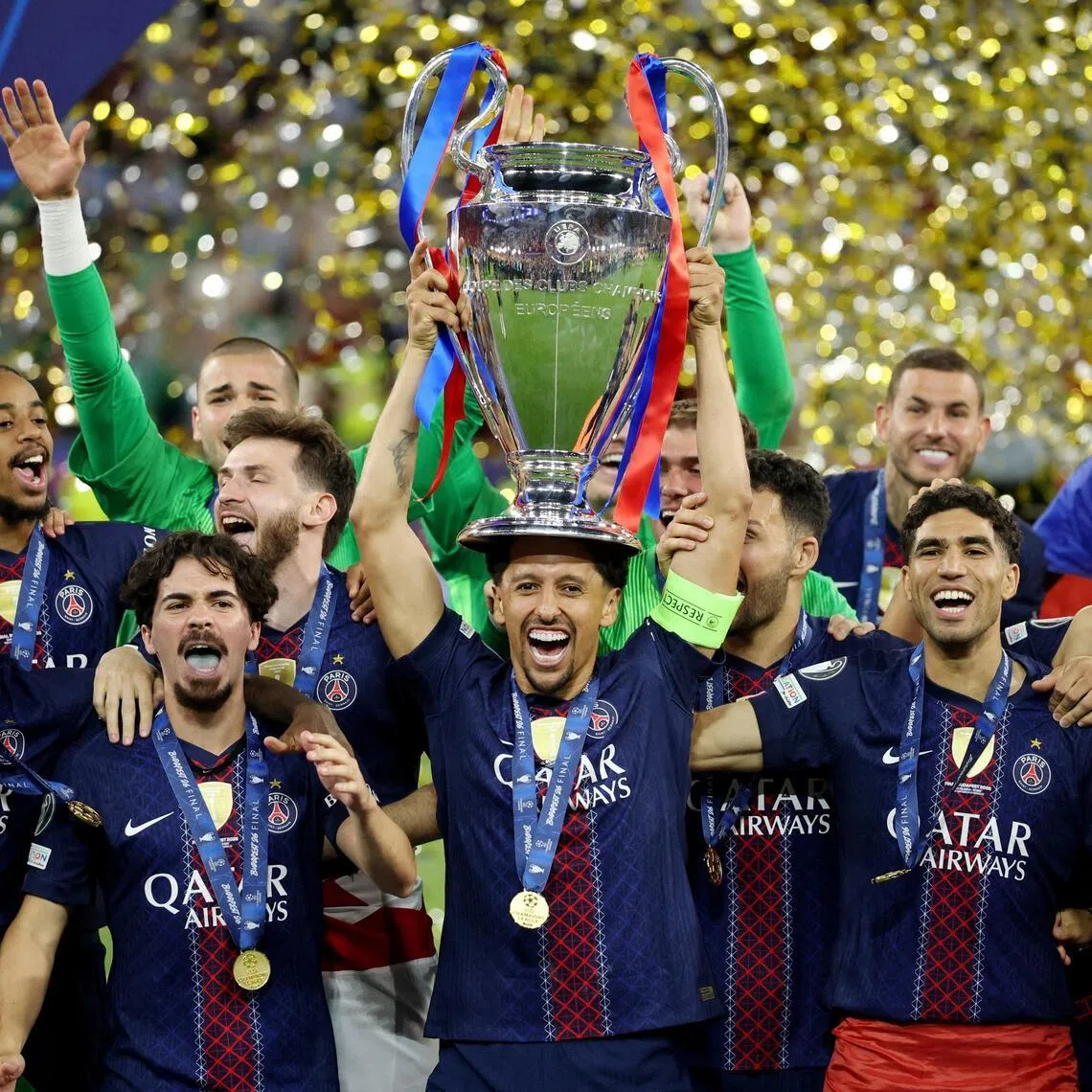 Paris St Germain's Marquinhos lifting the trophy on May 30, as he celebrates winning the UEFA Champions League with teammates.