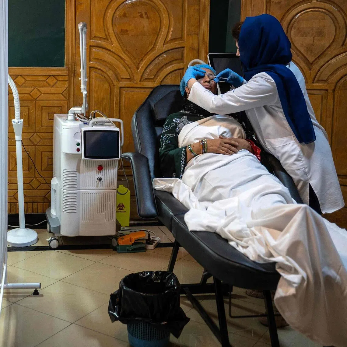In this photograph taken on September 3, 2025, members of a medical staff attend Afghan women at a beauty clinic in Kabul. Decked with fake crystal chandeliers and velvet sofas, cosmetic surgery clinics in Afghanistan's capital are a world away from the austerity of Taliban rule, where Botox, lip filler and hair transplants reign. (Photo by Wakil KOHSAR / AFP) / To go with 'Afghanistan-Social-Cosmetic-Surgery' , REPORTAGE by Claire GOUNON
