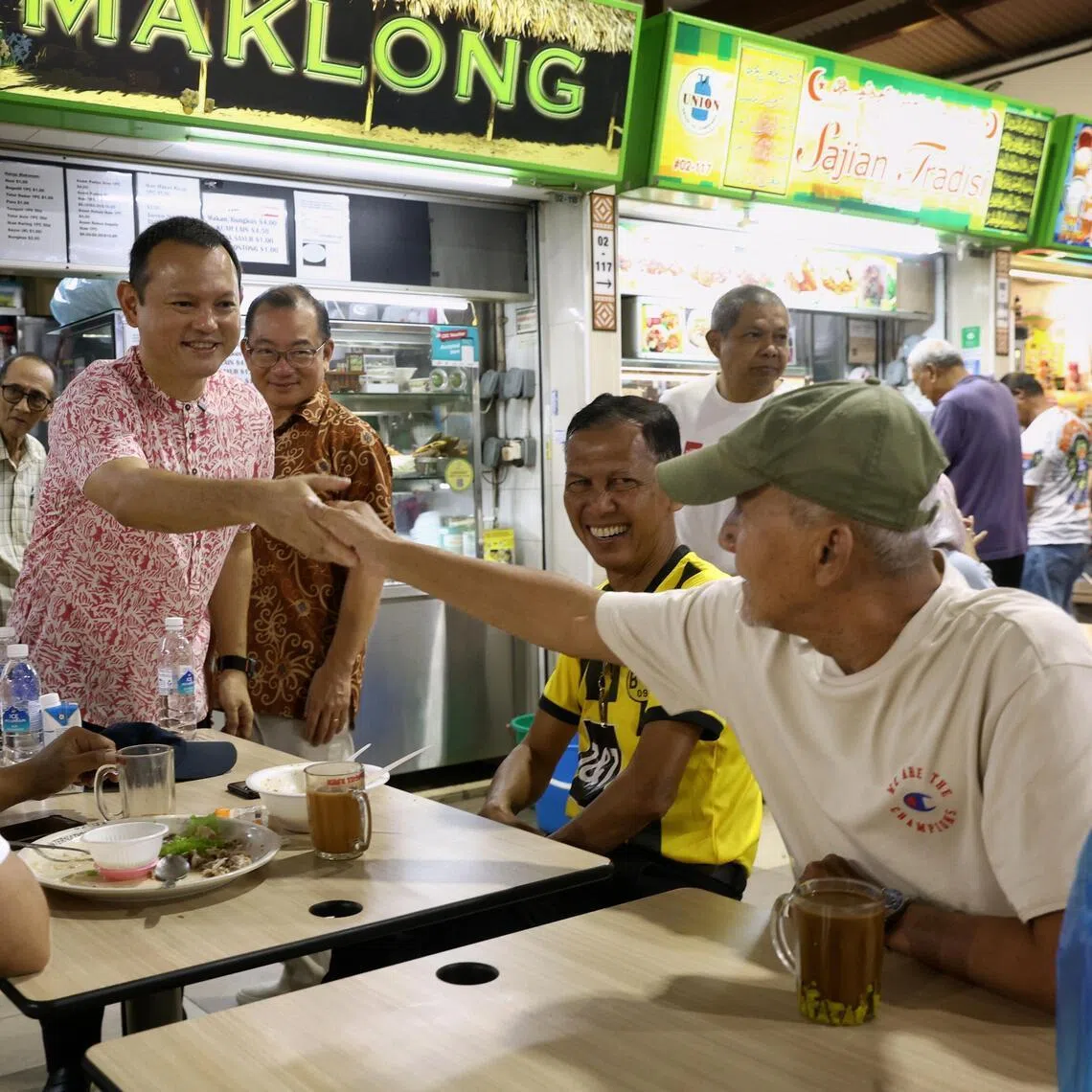 Acting Minister-in-charge of Muslim Affairs Zaqy Mohamad (centre left) and MP for Marine Parade-Braddell Heights GRC and Speaker of Parliament Seah Kian Peng (centre right) greeting members of the public at Geylang Serai Market and Food Centre on July 26.