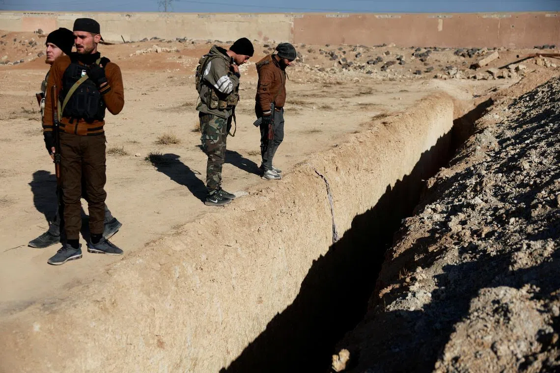 Fighters of the ruling Syrian body inspect the site of a mass grave from the rule of Syria's Bashar al-Assad, according to residents, after the ousting of al-Assad, in Najha, Syria, December 17, 2024. REUTERS/Ammar Awad