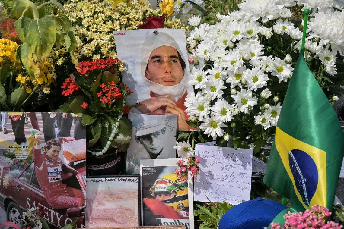 TOPSHOT - People lay flowers at the grave of Brazilian F1 driver Ayrton Senna in Sao Paulo, Brazil, on May 1, 2024, during the 30th anniversary of his death. Thirty years after his death at the San Marino Grand Prix, Ayrton Senna is still adored in Formula One, a sport his fatal accident reshaped. The 34-year-old Brazilian was leading at Imola on May 1, 1994, when he went off the track at the Tamburello curve and smashed into a concrete wall. (Photo by Nelson ALMEIDA / AFP)