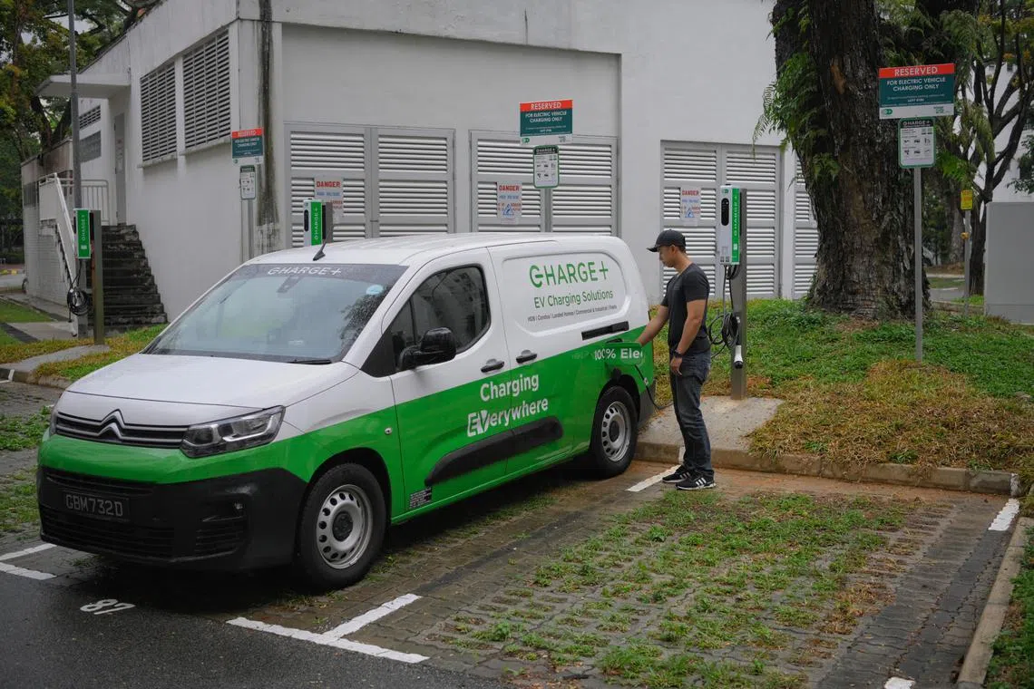 An employee from Charge+ charges an electric vehicle during a demonstration at a public electric vehicle charger at the Block 209 Jurong East St 21 carpark on November 7, 2023.