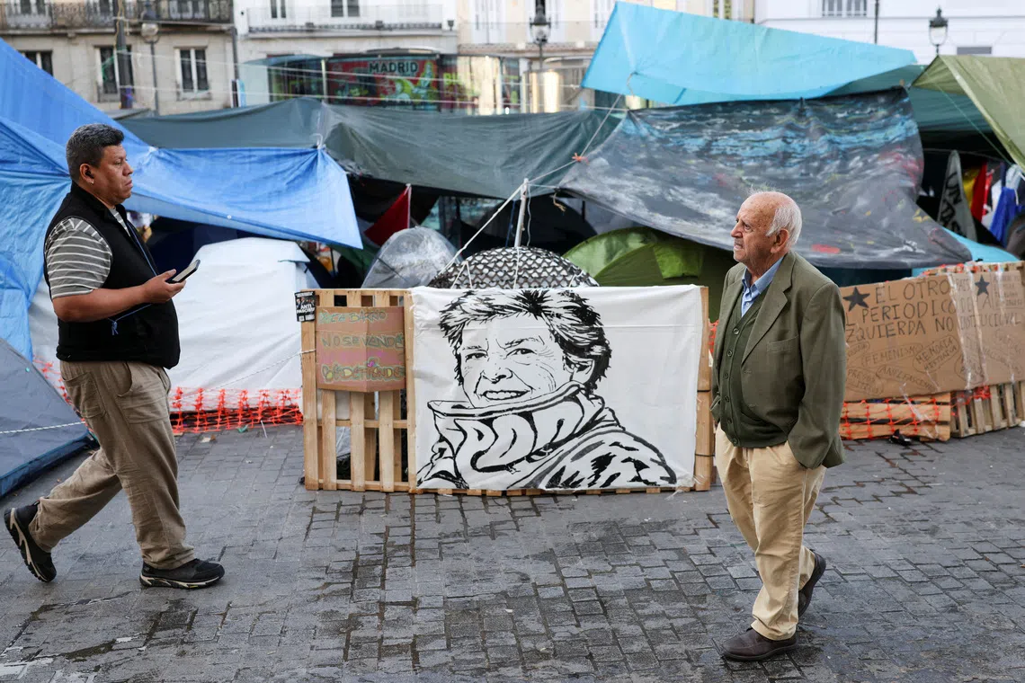 FILE PHOTO: People walk past a sign with the face of the late Maricarmen Abascal, an 87-year-old woman whose eviction sparked housing protests in Spain, at the protest camp at Puerta del Sol square in Madrid, Spain, October 10, 2026. REUTERS/Alejandro Martinez Velez/File Photo