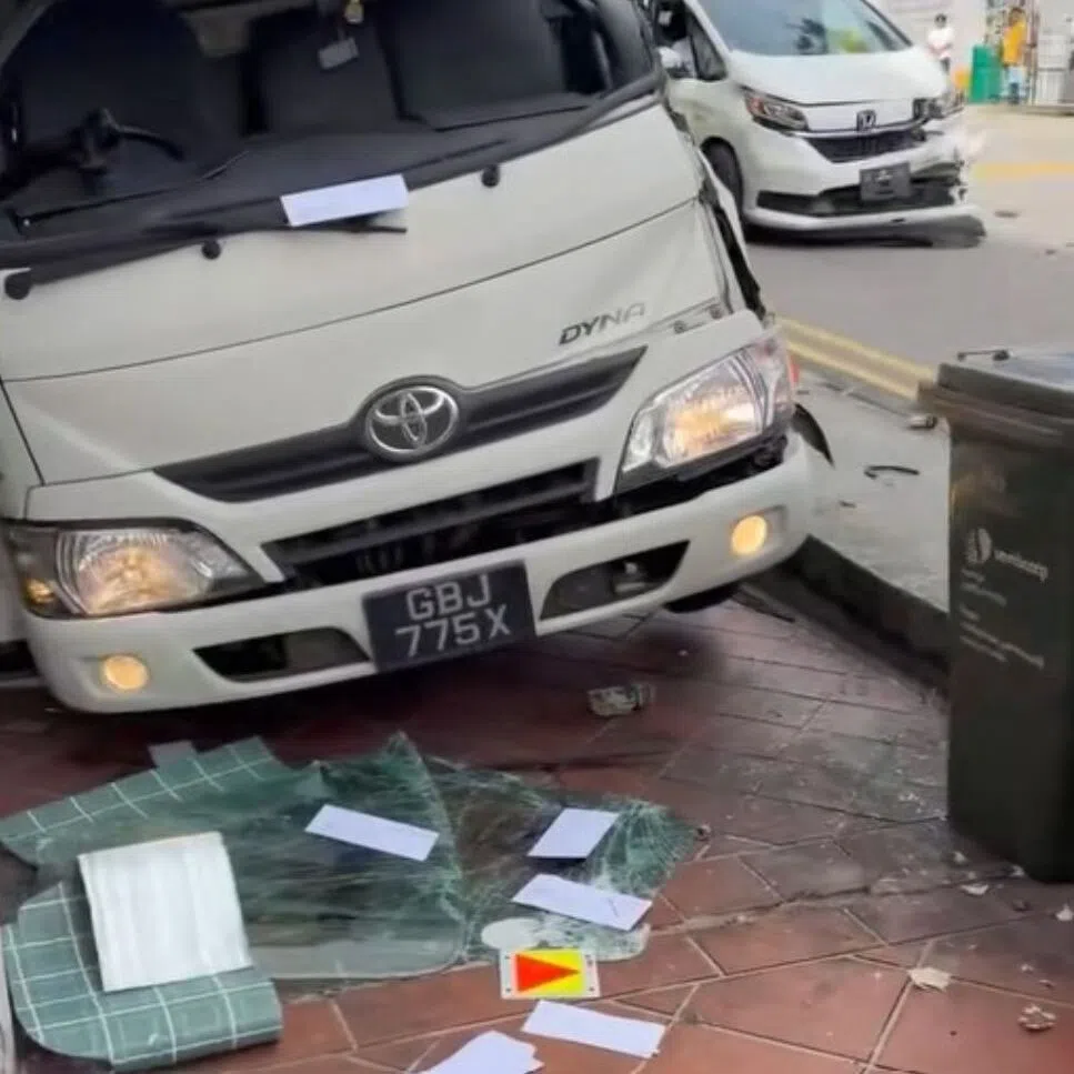 The lorry appears to be off the road and on the pedestrian footpaths outside a row of shops.