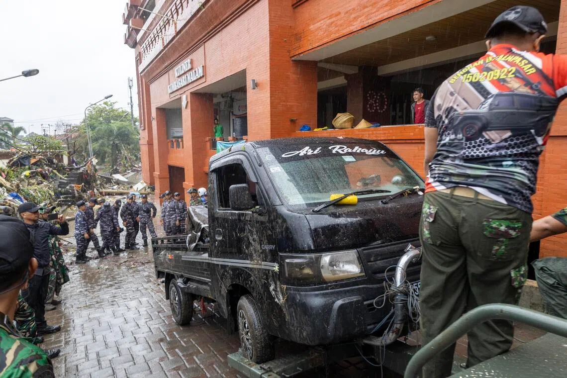 People and military personnel cleaning up a street after a flood in Denpasar, Bali on Sept 10. 