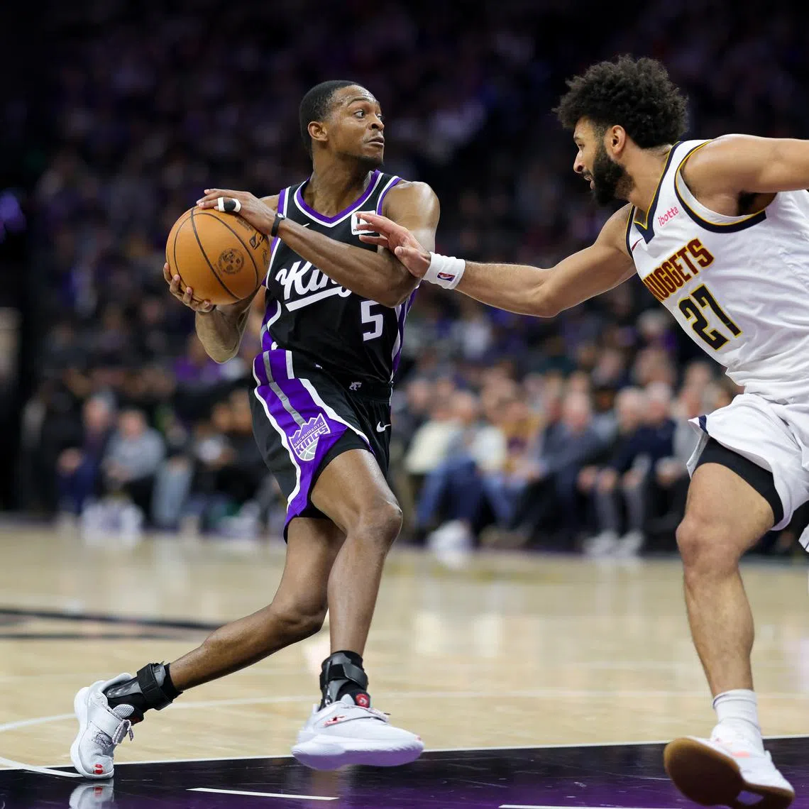 Dec 16, 2024; Sacramento, California, USA; Sacramento Kings guard De'Aaron Fox (5) controls the ball against Denver Nuggets guard Jamal Murray (27) during the third quarter at Golden 1 Center. Mandatory Credit: Sergio Estrada-Imagn Images
