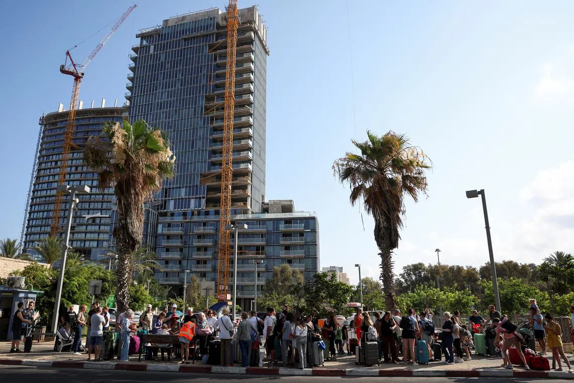 Foreign nationals wait in line to board a bus to be evacuated from Israel, amid the Iran-Israel conflict, in Tel Aviv, Israel, June 24, 2025. REUTERS/Violeta Santos Moura