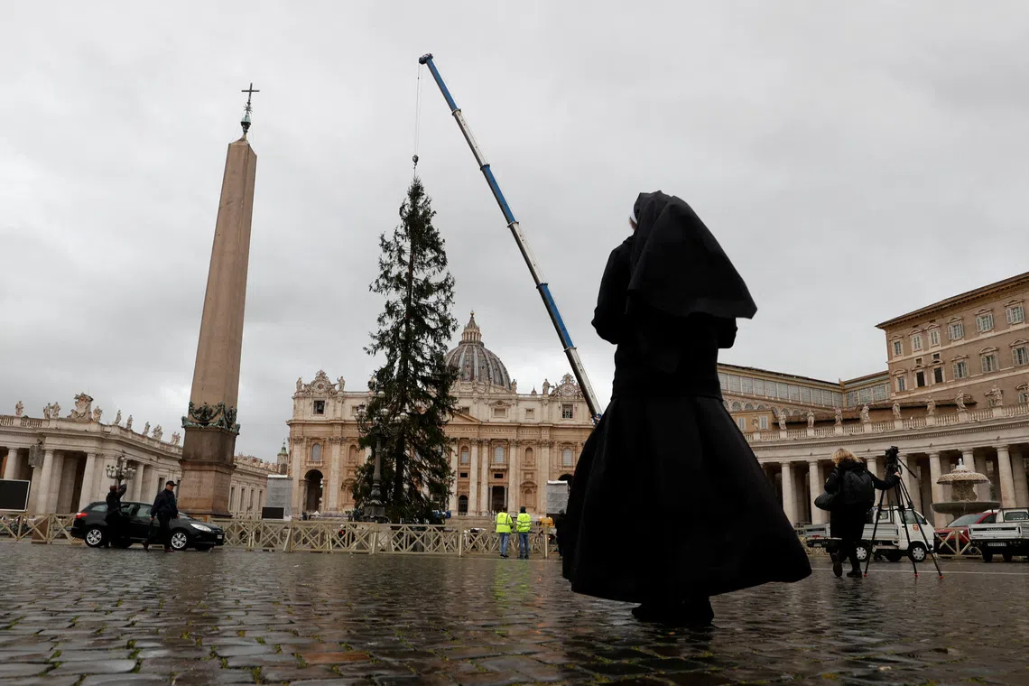 A nun takes a photo of the Christmas tree in St. Peter's Square ahead of the festive season at the Vatican, November 22, 2024. REUTERS/Ciro De Luca
