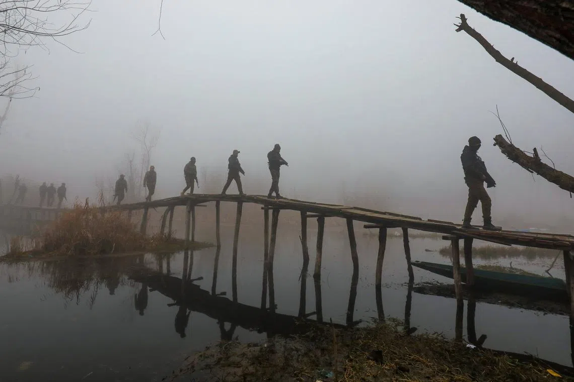Indian policemen patrolling on a wooden bridge on a cold and foggy day in Srinagar, Kashmir, India, Dec 26, 2023. 