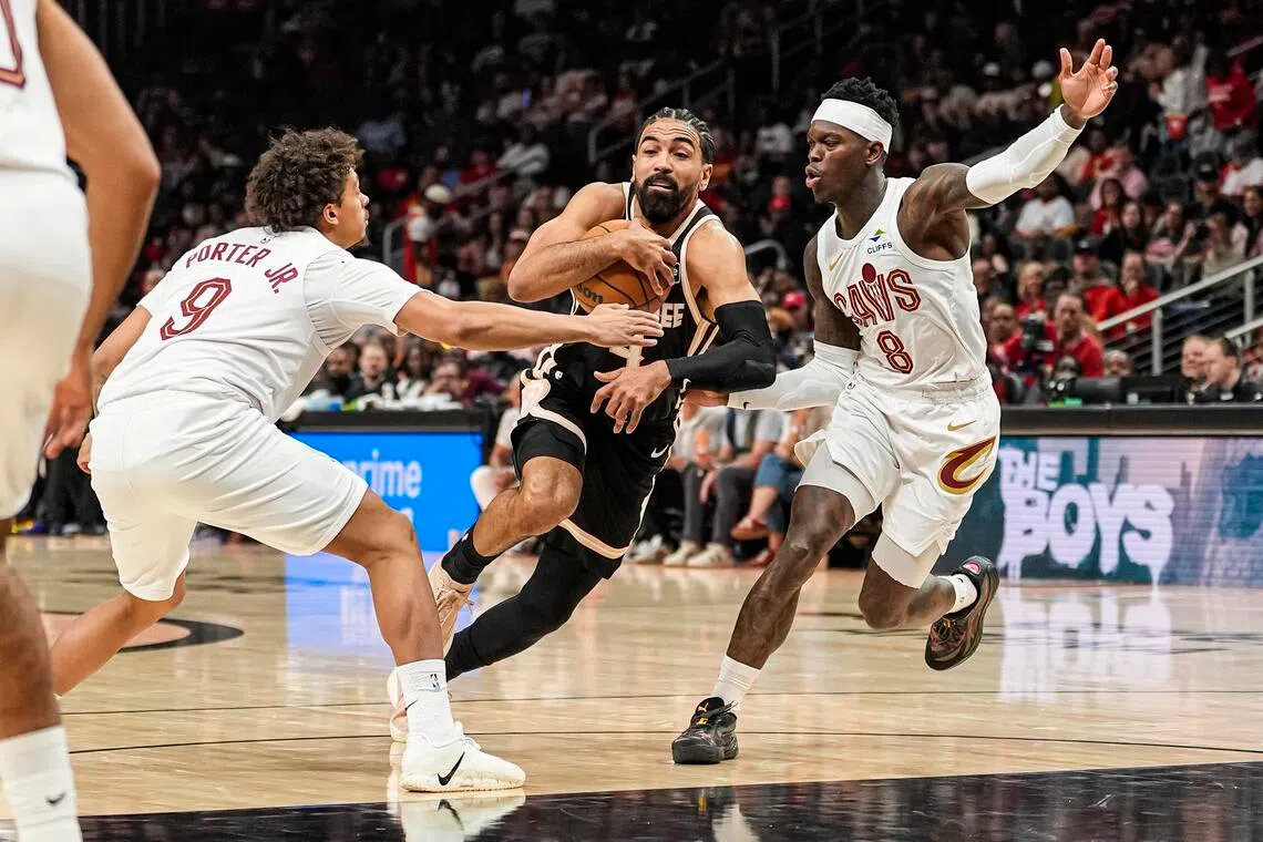 Atlanta Hawks guard Gabe Vincent tries to go between Cleveland Cavaliers guards Craig Porter Jr.  and Dennis Schroder during the first half at State Farm Arena.