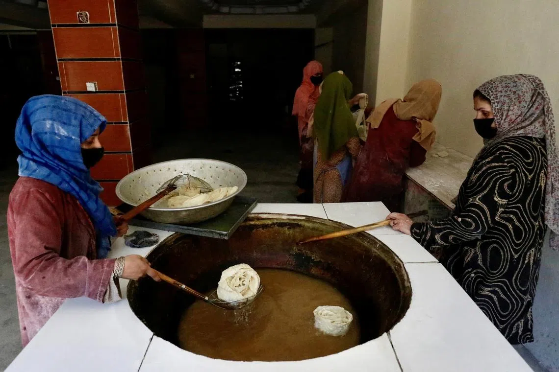FILE PHOTO: Afghan women fry traditional cookies inside a bakery in Kabul, Afghanistan, May 5, 2024. REUTERS/Sayed Hassib/File Photo