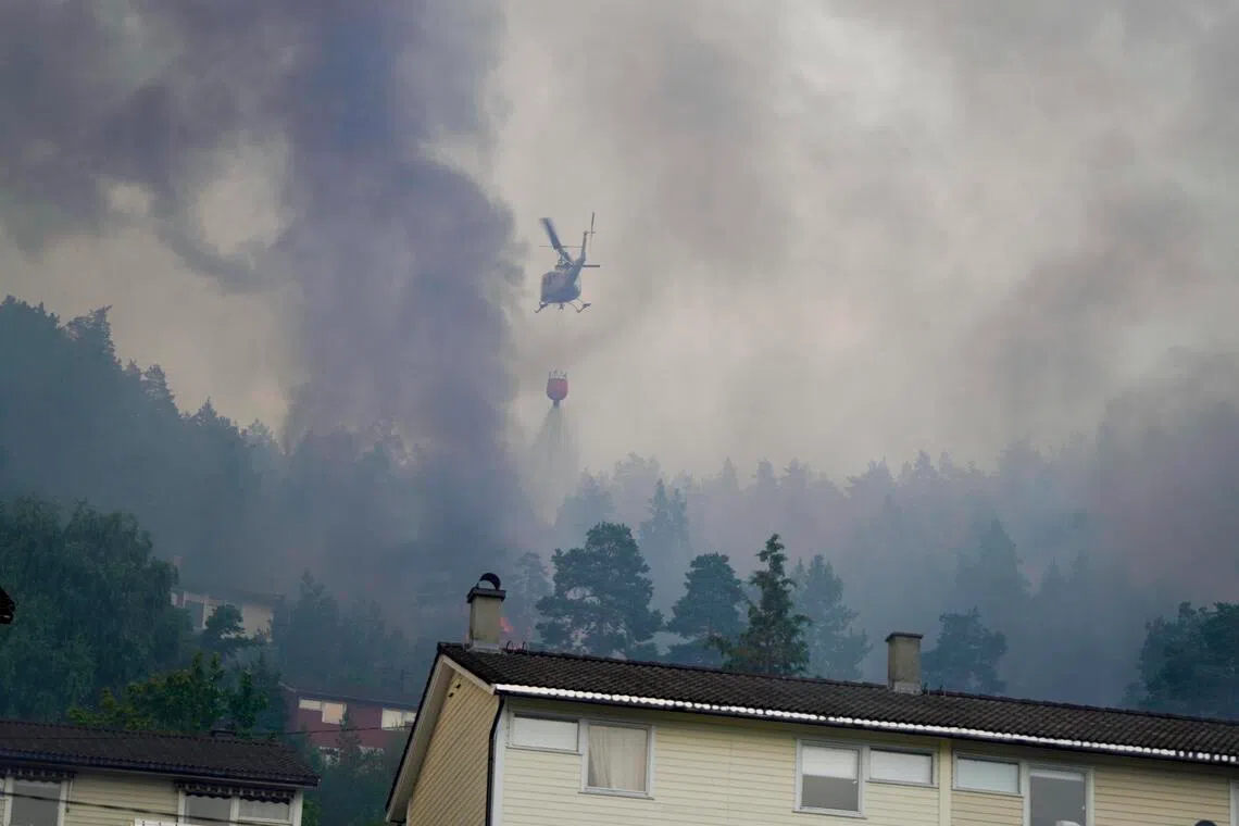 A helicopter dropping water on a huge fire that destroyed more than 100 homes in Drammen, Norway, on July 17.
