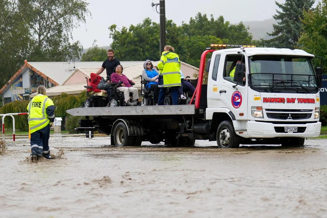 A photo taken on Feb 14, 2023, shows a group of wheelchair-bound people being rescued from a flooded area in the North Island city of Napier, New Zealand. 