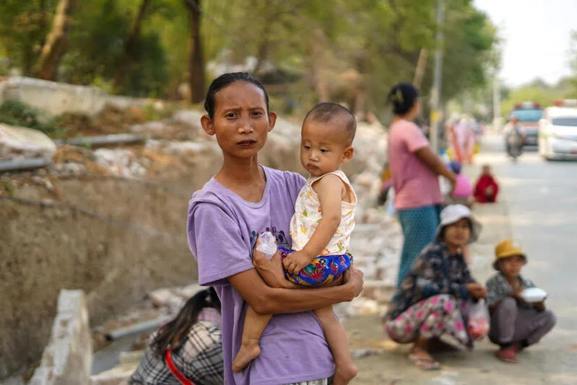 A mother holds up her child as she stands on a roadside waiting for a donation of relief supplies in Sagaing, Myanmar, on April 2.