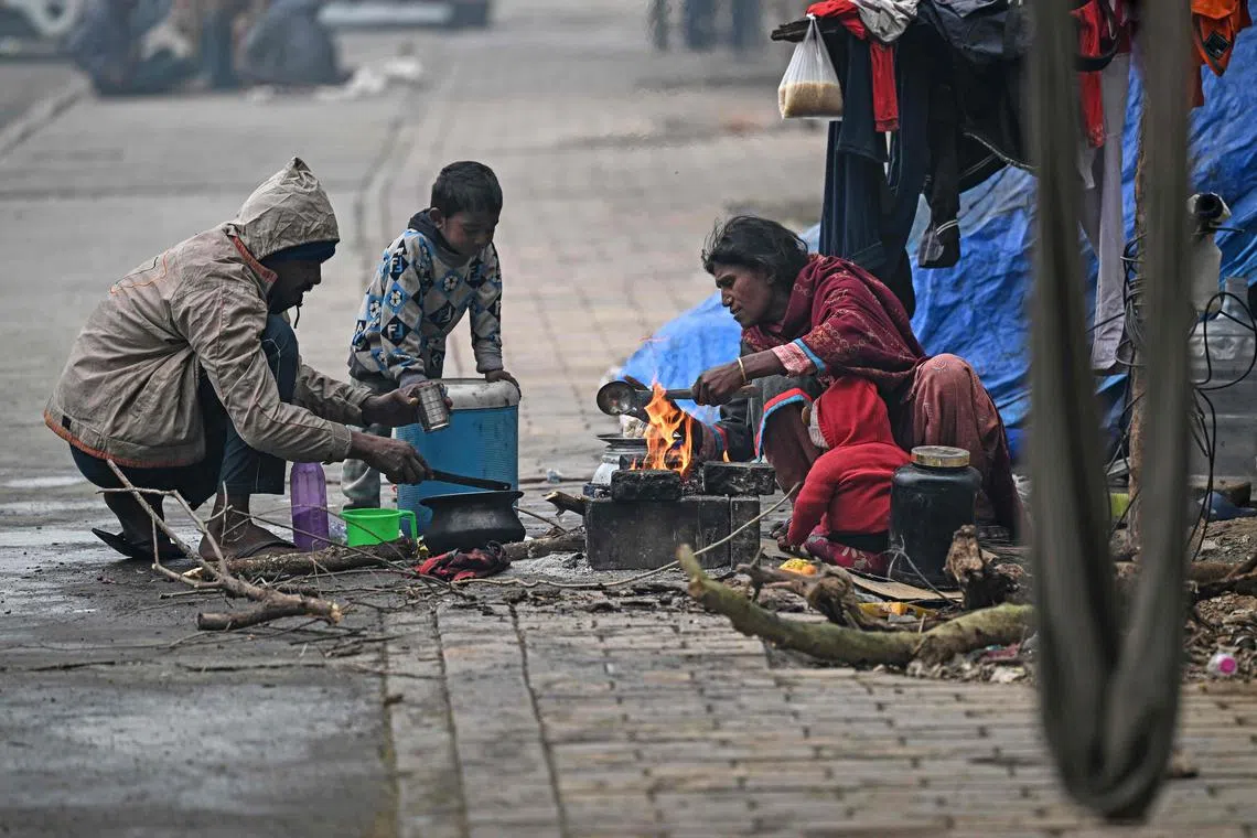 A homeless family cooks food along side of the road on a cold winter morning in New Delhi on Dec 23, 2024.