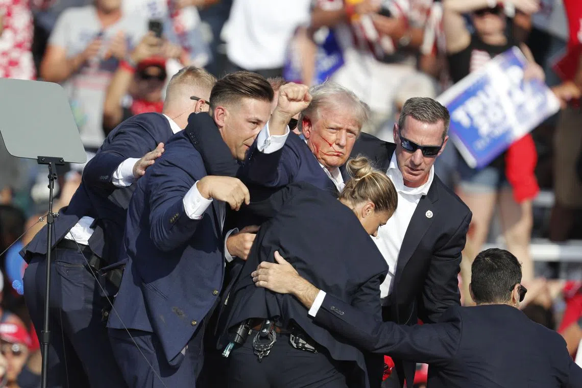 epa11756146 Former US President and Republican candidate Donald Trump (C) is rushed off stage by Secret Service agents after being shot at during a presidential campaign rally at the Butler Farm Show Inc. in Butler, Pennsylvania, USA, 13 July 2024. Trump was shot in the ear in an attempted assassination during the event. EPA-EFE/DAVID MAXWELL