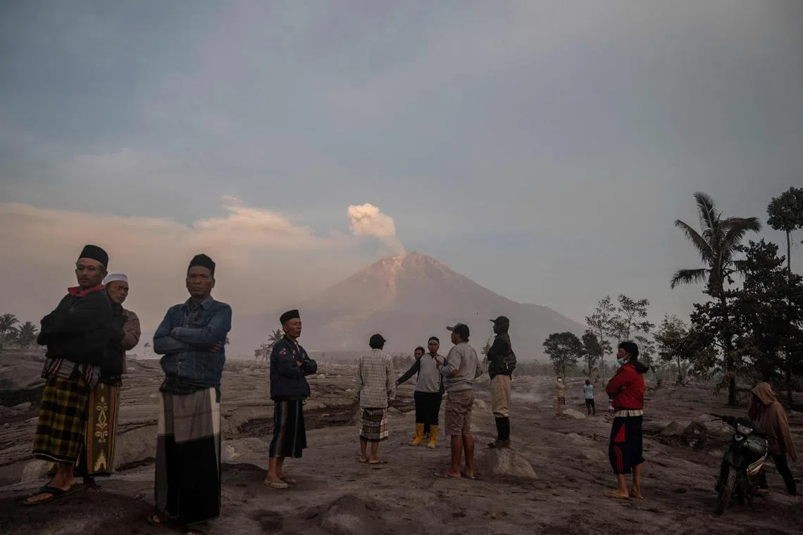 People stand before Mount Semeru following a volcanic eruption at Kajar Kuning village in Lumajang on Dec 5, 2022.