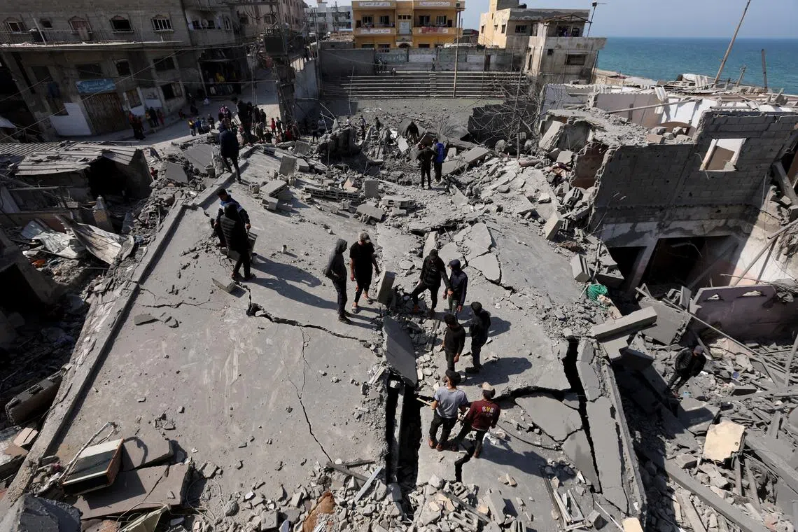 Palestinians inspect the site of an Israeli strike on a residential building, in Deir Al-Balah in the central Gaza Strip March 18, 2025. REUTERS/Ramadan Abed