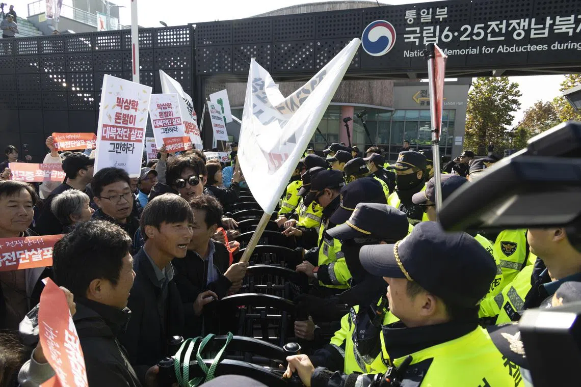 South Korean police officials (right) block activists as they shout slogans during a protest to launch anti-North Korean leaflets.