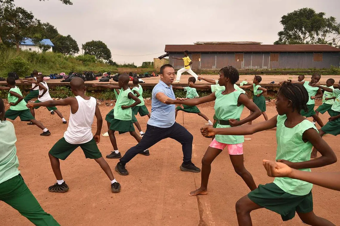 TOPSHOT - Chinese martial arts teacher Liu Wei (C) practices an excercise with students of the Fourah Bay College Secondary School in Freetown during a training session at the Confucius Institute University of Sierra Leone on October 15, 2024. The Chinese language and martial arts teachings are becoming popular amongst school children in several school institutions in Freetown and at the Fourah Bay College Secondary School since it was established in the country in 2012 to promote people to people traditional and cultural exchanges and for deepening friendship and cooperation with the People's Republic of China. (Photo by Saidu BAH / AFP)