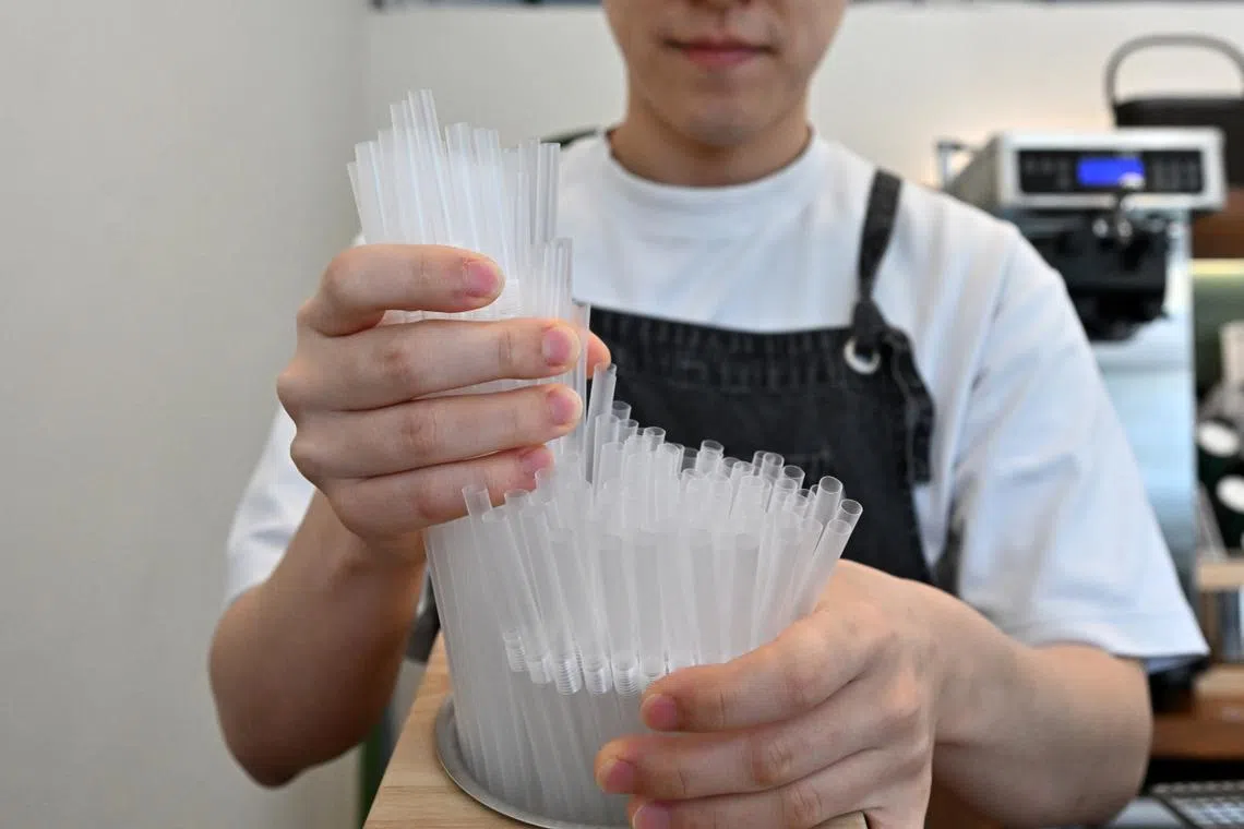 A cafe owner puts plastic straws out for customers following the Ministry of Environment's provisional extension of the grace period to implement its ban on disposable plastics, on Nov 8, 2023.