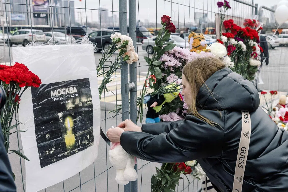 People lay flowers and stuffed toys near the Crocus City Hall on March 23, 2024, where at least 115 people were killed and more than 140 injured in an attack at the popular concert venue outside Moscow.