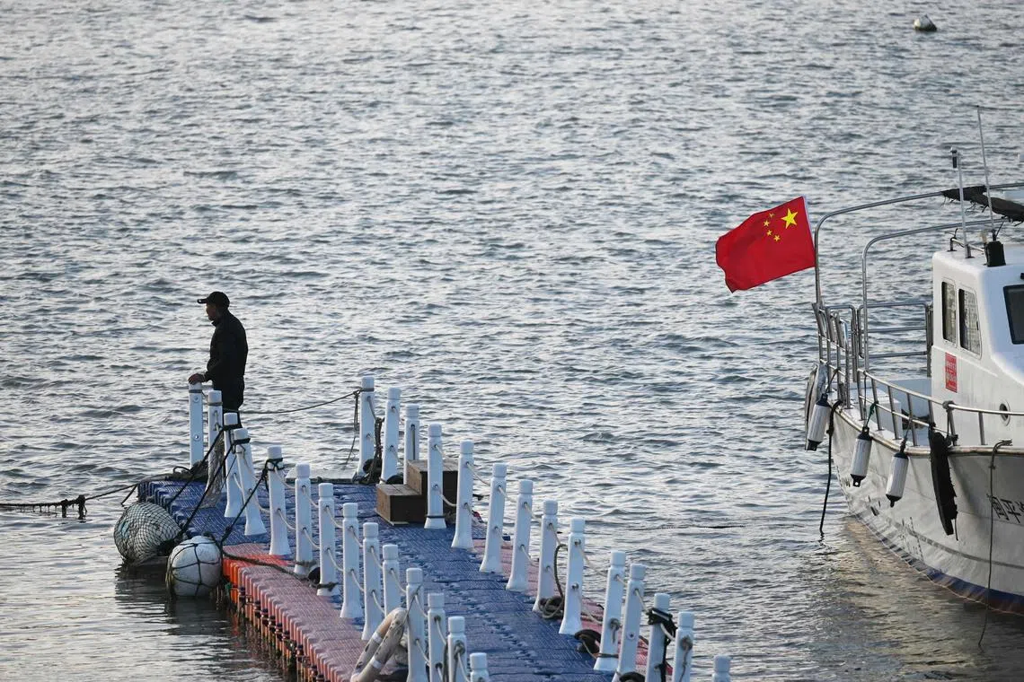 A man stands on a floating pier next to a tour boat with a Chinese flag at a harbour on Pingtan Island, in China's southeast Fujian province, the closest point in China to Taiwan’s main island, on Jan 13.