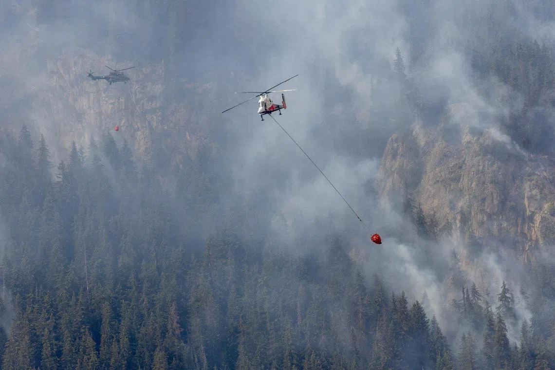 Helicopters fight against a wildfire on the flank of a mountain in Bitsch near Brig, Switzerland.