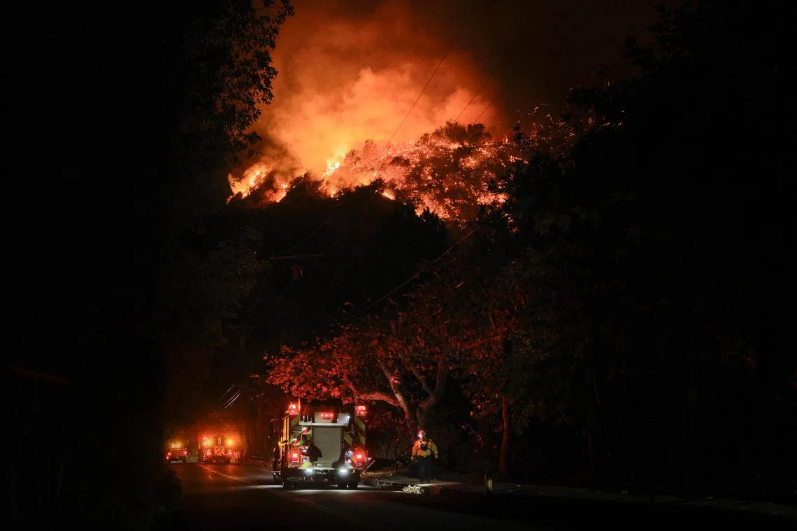 The hills burn above houses during the Palisades Fire in the Mandeville Canyon neighborhood of Los Angeles, on Jan 11.