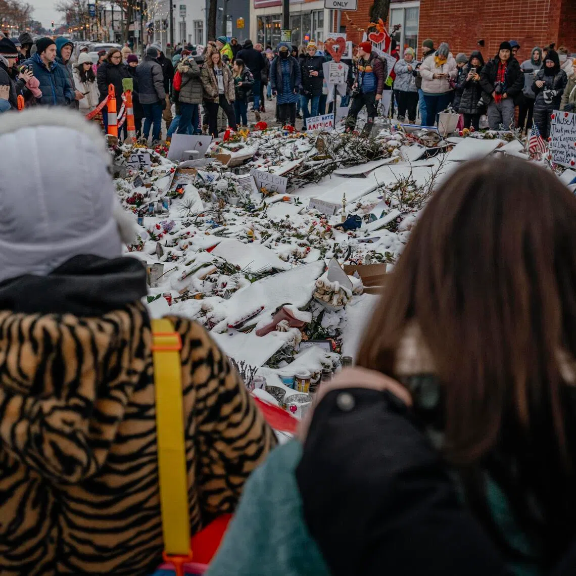 People gather near a makeshift memorial for Mr Alex Pretti at the site where he was fatally shot by federal immigration agents in Minneapolis.
