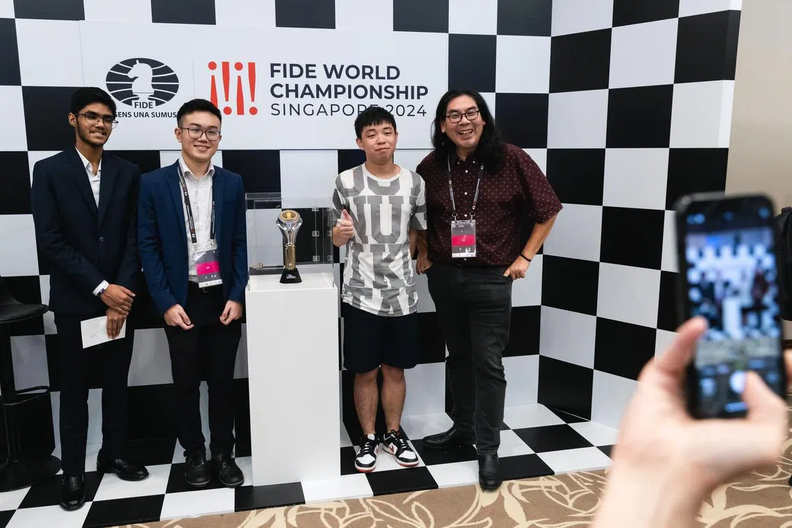 Singapore chess grandmasters Siddharth Jagadeesh (far left), Tin Jingyao (second from left) and Wong Meng Kong (right) posing for a photo with a fan after a question and answer session held at the Equarius Hotel on Dec 9.