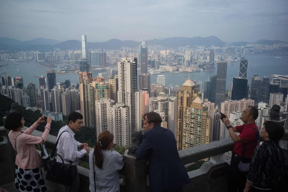(FILES) In this file photo taken on October 30, 2019 tourists chat and take photos as they visit Victoria Peak in Hong Kong. - Travellers returning to China from January 8, 2023 will no longer have to quarantine, removing one of the main barriers to travel for the country's population, and sparking a frenzy of trip planning for thousands ready to return to top Asian tourist spots. (Photo by Anthony WALLACE / AFP)