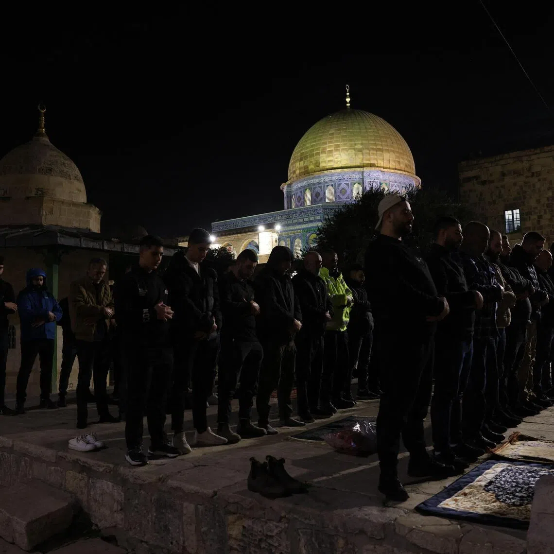 Palestinian Muslim worshippers perform Taraweeh prayers near the Dome of the Rock Shrine at the Al-Aqsa mosque compound.
