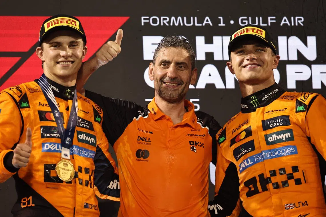 TOPSHOT - McLaren's Australian driver Oscar Piastri, McLaren team principal Andrea Stella and McLaren's British driver Lando Norris pose on the podium after the Bahrain Formula One Grand Prix at the Bahrain International Circuit in Sakhir on April 13, 2025. (Photo by Fadel SENNA / AFP)
