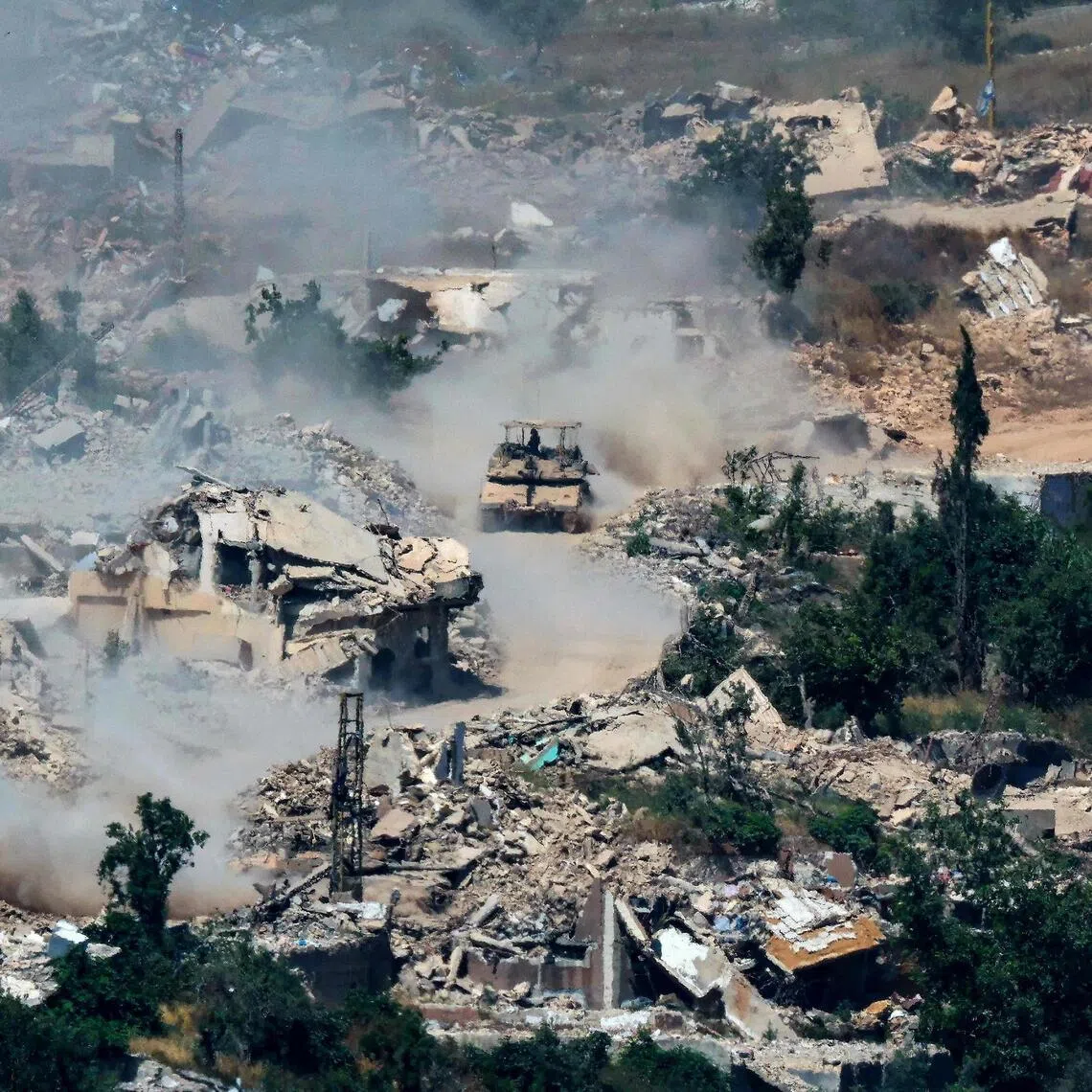 This picture taken from a position in the Upper Galilee in northern Israel, near the Israel-Lebanon border shows Israeli Merkava tanks driving along a road past destroyed buildings in southern Lebanon on June 17.