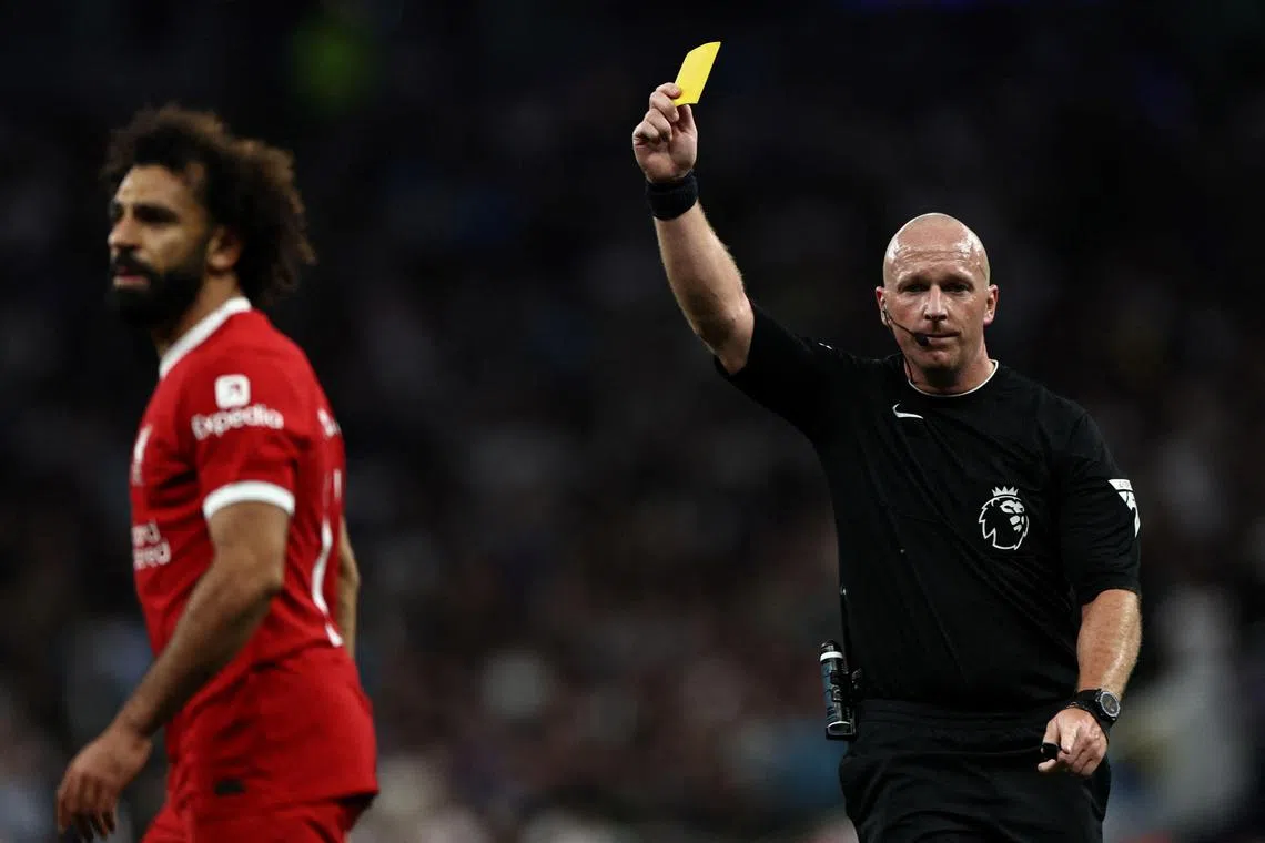 Referee Simon Hooper gives a yellow card to Liverpool's Mohamed Salah during a Premier League game.