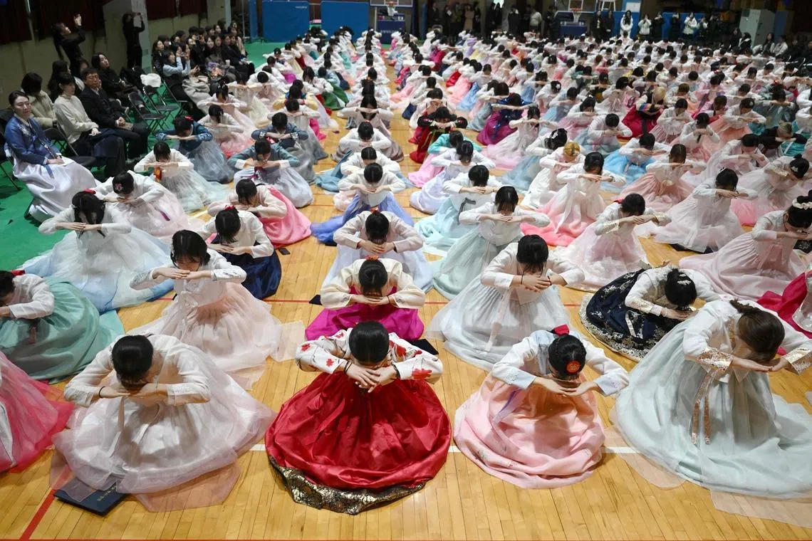South Korean students wearing traditional hanbok dresses bow as they attend a graduation and coming-of-age ceremony at a girls' high school in Seoul on Feb 5, 2026. Around 300 students attended the event, which symbolises the transition of children into adulthood and aims to teach participants manners and responsibility. 