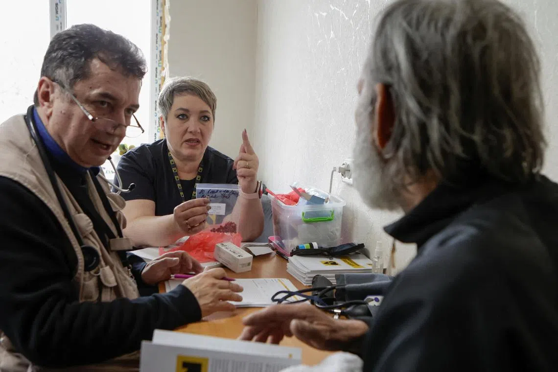 Doctors of the International Rescue Committee speak to a resident during a medical inspection in the village of Savyntsi, in Kharkiv region in Ukraine.  