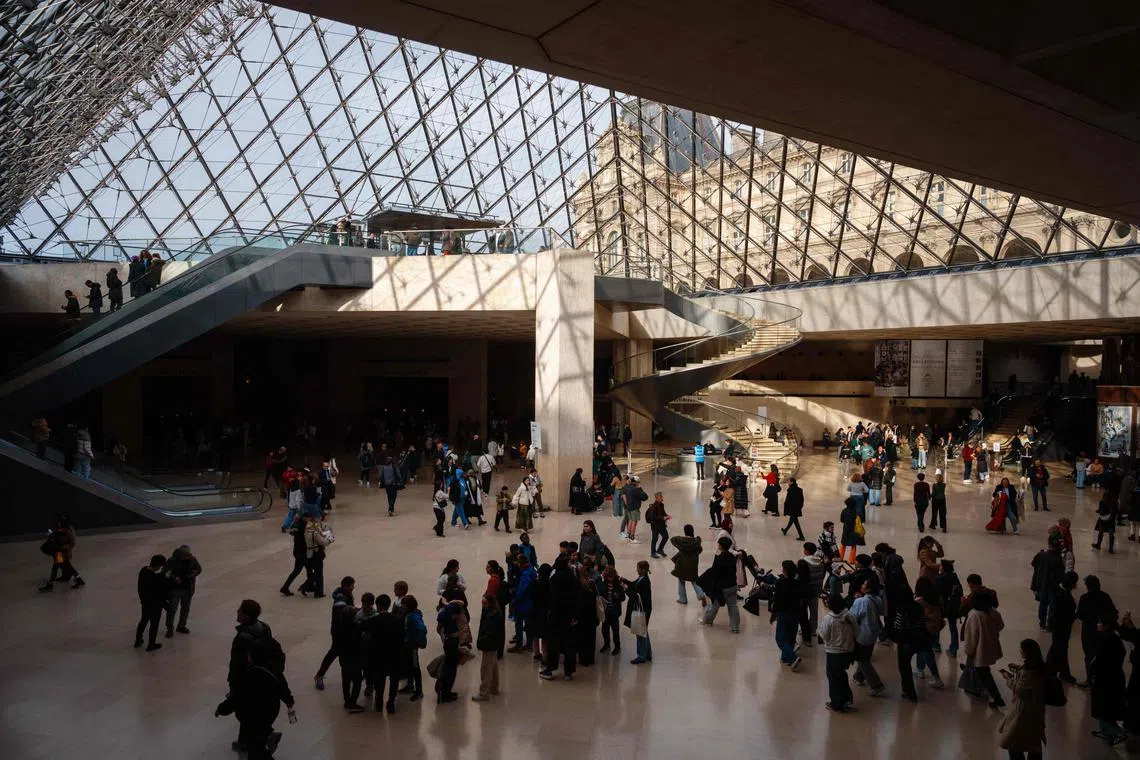 Visitors walk under the Louvre Pyramid designed by I.M. Pei at the Louvre Museum in Paris on Jan 23.