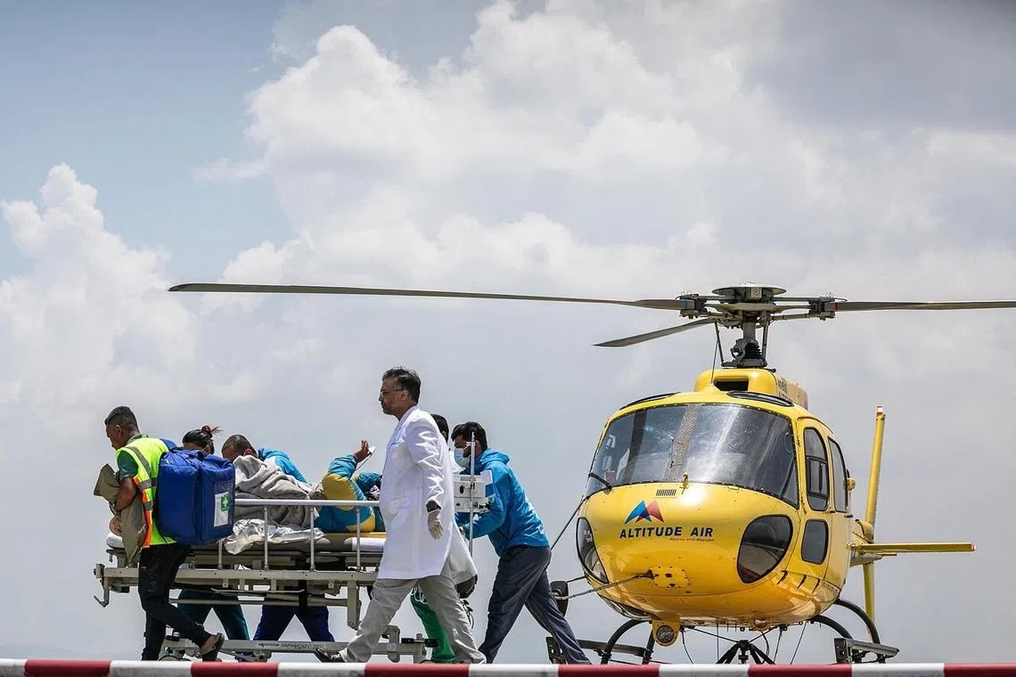 Medics and rescuers transfering mountaineer Dawa Sherpa from a helicopter upon his arrival at the HAMS Hospital in Kathmandu on June 4. The Nepali climbing guide who went missing on Mount Everest for six days and was believed to be dead had been found alive after crawling alone towards the Base Camp, officials said on June 4. 