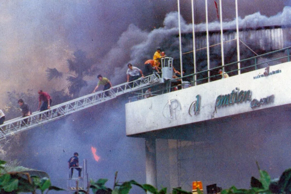 Survivors climb down a fire escape ladder from the Royal Jomtien Resort Hotel’s entrance canopy.