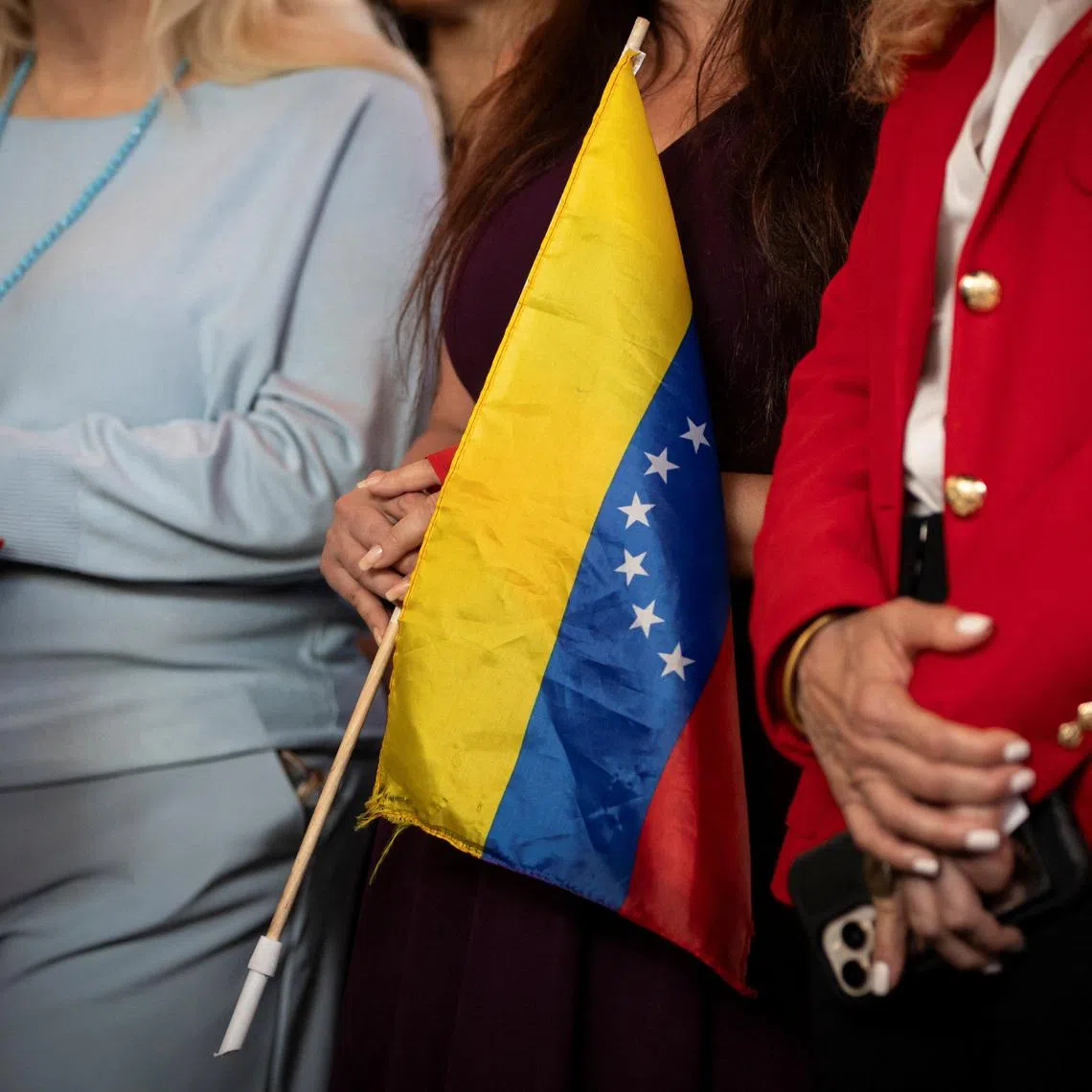 A woman holds a Venezuelan flag during a press conference on the U.S. strikes in Venezuela, in Doral, Miami-Dade County, Florida, U.S., January 5, 2026. REUTERS/Marco Bello